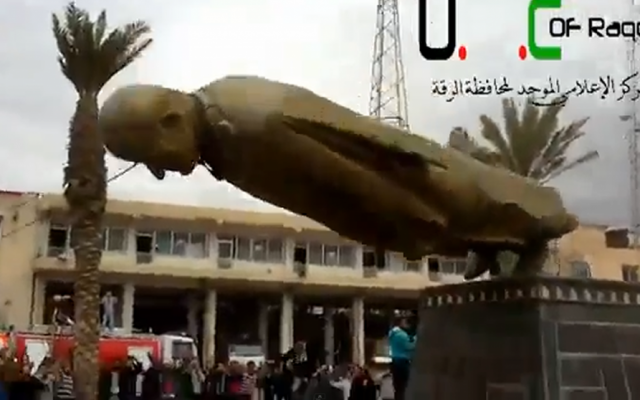 Residents of Raqqa topple a statue of Syrian President Bashar Assad's father and predecessor, Hafez Assad, on Monday, February 4, 2013. (photo credit: image capture from YouTube video) Residents of Raqqa topple a statue of Syrian President Bashar Assad's father and predecessor, Hafez Assad, on Monday, February 4, 2013. (photo credit: image capture from YouTube video)