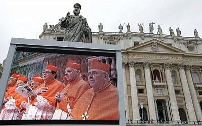 A giant monitor in St. Peter's Square at the Vatican, shows cardinals praying, before filing into the Sistine Chapel for the conclave to elect the next pope, Tuesday, March 12, 2013. (photo credit: AP/Gregorio Borgia)