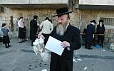 Illustrative photo of an Ultra-Orthodox Jewish man holding a chicken later to be slaughtered as part of a Kaparot ritual (photo credit: Pierre Terdjman /Flash90)