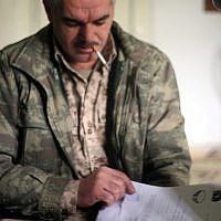 Commander Jamil Radoon looks through the gun register he created. The register lists the serial number of every gun issued and the identity of the recipient. In Qalaat al-Madik. (photo: Eliyahu Kamisher)
