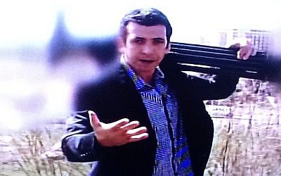Guy Lerer, with a tripod on his shoulder, in an image with a blurred background filmed outside what he said was the building housing servers with some of Israel's most critical computer information (photo credit: Channel 10 screenshot)