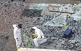 Two men in hazardous materials suits put numbers on the shattered glass and debris as they investigate the scene at the first bombing on Boylston Street in Boston Tuesday, April 16, 2013 near the finish line of the 2013 Boston Marathon, a day after two blasts killed three and injured over 170 people (photo credit: Elise Amendola/AP)
