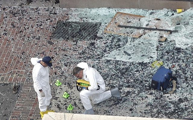 Two men in hazardous materials suits put numbers on the shattered glass and debris as they investigate the scene at the first bombing on Boylston Street in Boston Tuesday, April 16, 2013 near the finish line of the 2013 Boston Marathon, a day after two blasts killed three and injured over 170 people (photo credit: Elise Amendola/AP) Two men in hazardous materials suits put numbers on the shattered glass and debris as they investigate the scene at the first bombing on Boylston Street in Boston Tuesday, April 16, 2013 near the finish line of the 2013 Boston Marathon, a day after two blasts killed three and injured over 170 people (photo credit: Elise Amendola/AP)