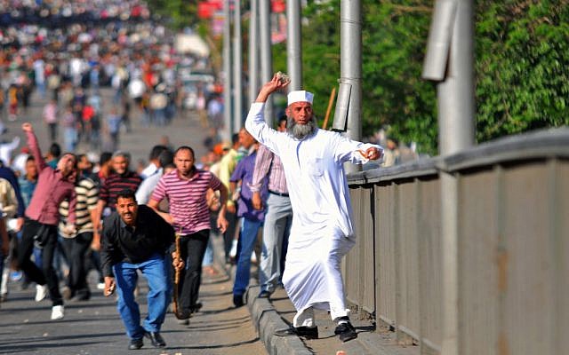 An Egyptian man throws a stone during clashes between rival groups of protesters in Cairo, Egypt, Friday, April 19, 2013. (photo credit: AP/Mostafa Darwish) An Egyptian man throws a stone during clashes between rival groups of protesters in Cairo, Egypt, Friday, April 19, 2013. (photo credit: AP/Mostafa Darwish)