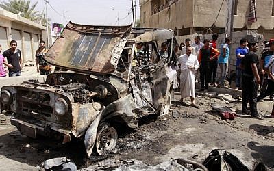 Civilians gather at the scene of a car bomb attack in the east Baghdad neighborhood of Kamaliya, Iraq, Monday, April 15, 2013 (photo credit: Khalid Mohammed/AP)