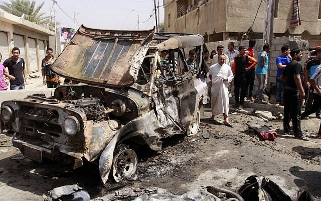 Civilians gather at the scene of a car bomb attack in the east Baghdad neighborhood of Kamaliya, Iraq, Monday, April 15, 2013 (photo credit: Khalid Mohammed/AP) Civilians gather at the scene of a car bomb attack in the east Baghdad neighborhood of Kamaliya, Iraq, Monday, April 15, 2013 (photo credit: Khalid Mohammed/AP)