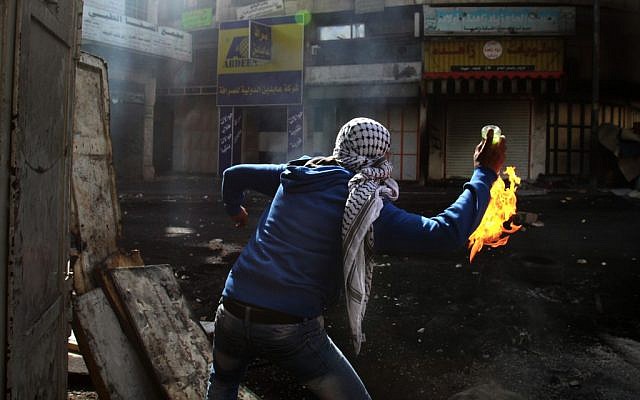 Illustrative photo of a young Palestinian hurling a firebomb in Hebron. (AP/Nasser Shiyoukhi)