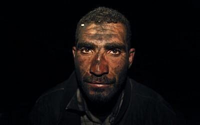 Palestinian worker Hamuda Mahdi, who oversees production of coal at night, poses for a photograph at one of the few local charcoal manufacturing shops east of Gaza City. (AP Photo/Hatem Moussa)
