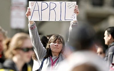 Justine Franco of Montpelier, Vt., holds up a sign near Copley Square in Boston looking for her missing friend, April, who was running in her first Boston Marathon Monday, April 15, 2013. Two bombs exploded near the finish line of the marathon on Monday, killing at least two people and injuring at least 23 others. (photo credit: AP/Winslow Townson)