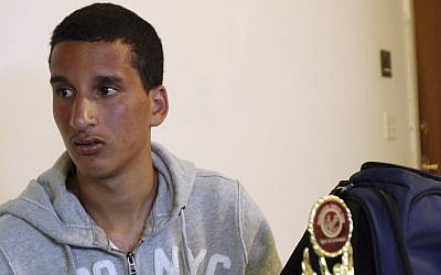 Salah Eddin Barhoum in his apartment in Revere, Mass., with one of the trophies he won in an athletic competition, and the bag he was carrying on Monday near the finish line of the Boston Marathon, Thursday, April 18, 2013. (photo credit: AP/Rodrique Ngowi)