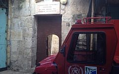 An Israeli fire vehicle parked outside the entrance to the Church of St. John the Baptist, lightly damaged in a small blaze overnight (photo credit: Matti Friedman/Times of Israel)