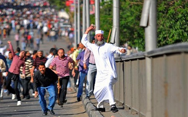 An Egyptian man throws a stone during clashes between rival groups of protesters in Cairo, Egypt, Friday, April 19, 2013 (AP Photo/Mostafa Darwish)