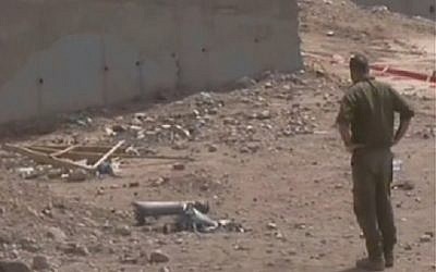 An IDF soldier looks at the remains of a Grad rocket fired on the southern city of Eilat. (photo credit: image capture Channel 2)