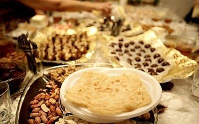 An Israeli family celebrates the Mimouna, a traditional holiday celebrated by Moroccan Jews at the end of Passover, by eating the traditional mufleta, a thin honey-covered pancake. (file photo; photo credit: Abir Sultan/Flash90)