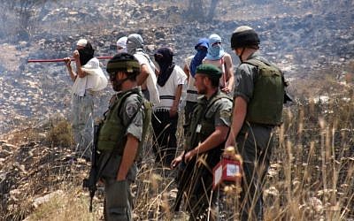 Masked settlers stand alongside IDF soldiers in the West Bank (photo credit: Wagdi Ashtiyeh/Flash90)
