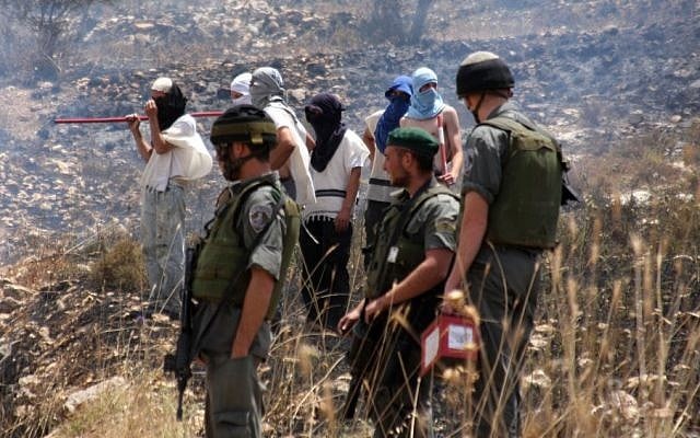 Masked settlers stand alongside IDF soldiers in the West Bank (photo credit: Wagdi Ashtiyeh/Flash90) Masked settlers stand alongside IDF soldiers in the West Bank (photo credit: Wagdi Ashtiyeh/Flash90)