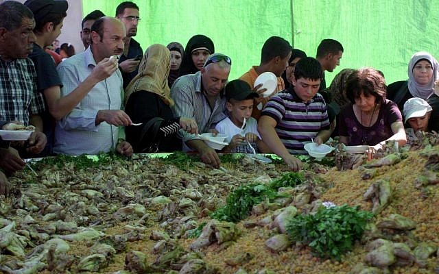 Ramallah residents serve themselves from a massive dish with chickpeas, cracked wheat (freekeh) and chicken (photo credit: Issam Rimawi/Flash 90)