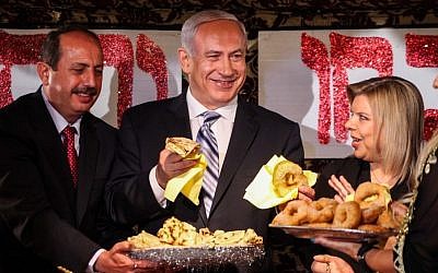 Prime Minister Benjamin Netanyau and his wife Sara enjoy 'mufletot' and traditional sweets at a colorful North African Mimouna celebration in Or Akiva, Monday. (photo credit: Avishag Shaar Yashuv/Flash90)