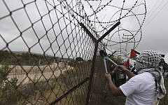 A Palestinian protester cuts part of the security barrier near the West Bank city of Ramallah on April 17. (photo credit: Issam Rimawi/Flash90)