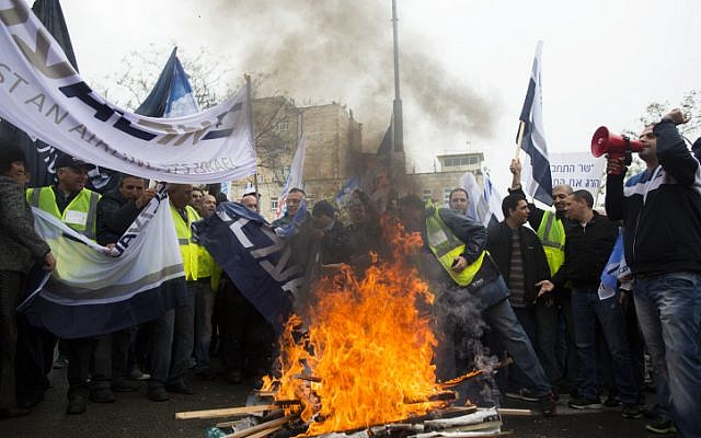 Israeli airline workers hold flags ans placards in front of tires burning during a demonstration outside the prime minister's office against the Open Skies agreement, on April 21, 2013 (photo credit: Yonatan Sindel/Flash90) Israeli airline workers hold flags ans placards in front of tires burning during a demonstration outside the prime minister's office against the Open Skies agreement, on April 21, 2013 (photo credit: Yonatan Sindel/Flash90)