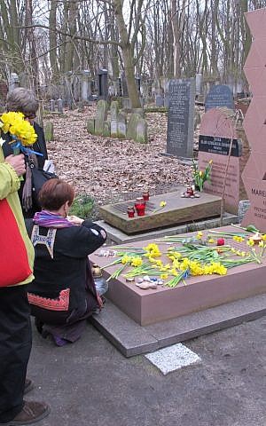 Observers placing daffodils at the grave of Marek Edelman, a commander of the Warsaw Ghetto uprising, in Warsaw's Jewish cemetery. (photo credit: Ruth Ellen Gruber/JTA)