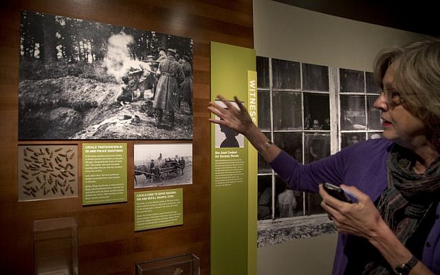 Museum curator Susan Bachrach discusses a group of photographs showing a local Ukrainian auxiliary policeman killing a Jewish woman and child in 1941, during a preview of the new April 30 exhibit 'Some Were Neighbors: Collaboration & Complicity in the Holocaust.' (photo credit: AP/Carolyn Kaster)