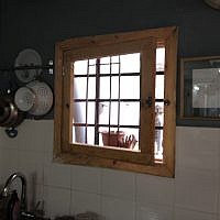 Pots and pans hanging next to the finished kitchen window (photo credit: Jessica Steinberg/Times of Israel)