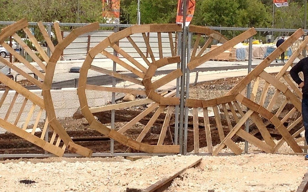 A local urban artist is creating a hand-constructed fence at the Station, made from recycled pieces of wood. (photo credit: Jessica Steinberg/Times of Israel)