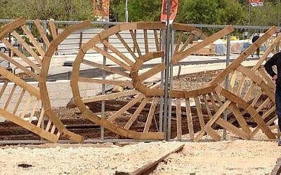 A local urban artist is creating a hand-constructed fence at the Station, made from recycled pieces of wood. (photo credit: Jessica Steinberg/Times of Israel)