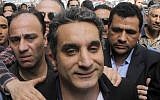 A bodyguard secures popular Egyptian television satirist Bassem Youssef, who has come to be known as Egypt's Jon Stewart, as he enters Egypt's state prosecutors office to face separate accusations of insulting Islam and the country's Islamist leader in Cairo, Egypt, on March 31, 2013 (photo credit: AP Photo/Amr Nabil, File)