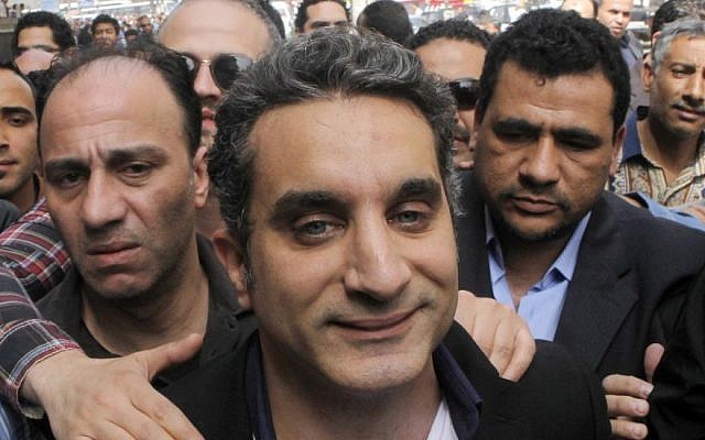 A bodyguard secures popular Egyptian television satirist Bassem Youssef, who has come to be known as Egypt's Jon Stewart, as he enters Egypt's state prosecutors office to face separate accusations of insulting Islam and the country's Islamist leader in Cairo, Egypt, on March 31, 2013 (photo credit: AP Photo/Amr Nabil, File)
