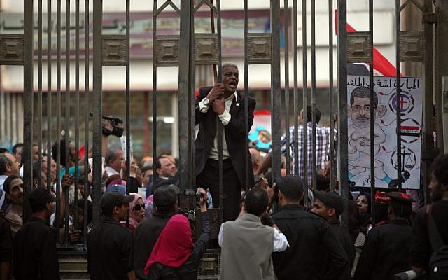 An Egyptian man chants slogans as another holds a cartoon of Egypt's president, Mohammed Morsi during a protest in front of the judges club in downtown Cairo, Egypt, Wednesday, April 24, 2013. (photo credit: AP/Khalil Hamra) An Egyptian man chants slogans as another holds a cartoon of Egypt's president, Mohammed Morsi during a protest in front of the judges club in downtown Cairo, Egypt, Wednesday, April 24, 2013. (photo credit: AP/Khalil Hamra)