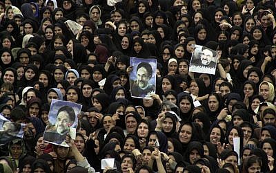 In this Monday, Sept. 30, 2002 file photo, Iranian women hold pictures of President Mohammad Khatami during a public welcoming ceremony at the Azadi stadium in the city of Rasht northwest of capital Tehran, Iran. (AP Photo/Vahid Salemi, file)