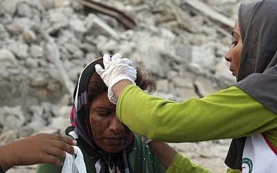 An Iranian woman receives medical treatment after a 6.1 magnitude earthquake struck southern Iran on Tuesday. Although 37 people were killed and 850 were injured, a nuclear plant in the region, Bushehr, was left unharmed. (photo credit: AP Photo/Fars News Agency, Mohammad Fatemi)