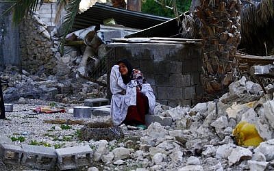 An Iranian woman reacts as she sits among the rubble of buildings after an earthquake struck southern Iran, in Shonbeh, Iran in April. (photo credit: AP/Fars News Agency, Mohammad Fatemi)