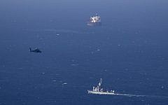 An Israeli military naval ship and an Israeli air force helicopter operate off the coast of Haifa on Thursday searching for debris from a downed drone. (photo credit:AP/Ariel Schalit)