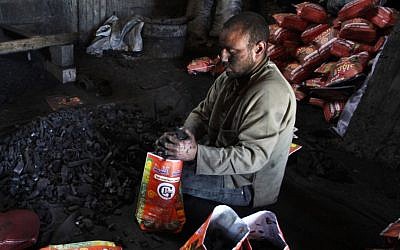 A Palestinian worker fills bags with coal to be sold, Jabalya refugee camp, northern Gaza Strip. (AP Photo/Hatem Moussa)