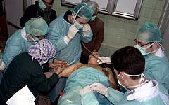 A Syrian victim who suffered an alleged chemical attack at Khan al-Assal village, according to SANA, receives treatment by doctors at a hospital in Aleppo. (photo credit: AP/SANA)