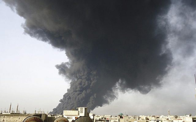Black smoke rises from an oil pipeline, in the Baba Amr neighborhood in Homs province, Syria. Syria’s vital oil industry is breaking down as rebels capture many of the country’s oil fields, with wells aflame and looters scooping up crude, depriving the government of much needed cash and fuel for its war machine against the uprising. (photo credit: AP/SANA) 