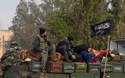 This Friday, Jan. 11, 2013 file citizen journalism image shows rebels from al-Qaida affiliated Jabhat al-Nusra, as they sit on a truck full of ammunition, at Taftanaz air base, that was captured by the rebels, in Idlib province, northern Syria (photo credit: AP/ENN)