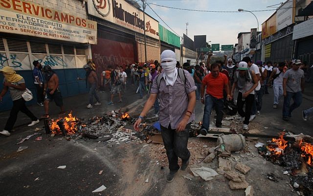 Opposition supporters and students cross a barricade during clashes with riot police in Caracas, Venezuela, on Monday, April 15, 2013. (photo credit: AP Photo/Fernando Llano) Opposition supporters and students cross a barricade during clashes with riot police in Caracas, Venezuela, on Monday, April 15, 2013. (photo credit: AP Photo/Fernando Llano)