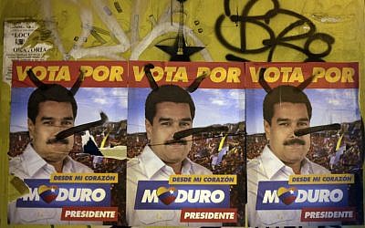 Defaced campaign signs of ruling party presidential candidate Nicolas Maduro cover a wall in Caracas, Venezuela, Friday, April 12 (photo credit: AP/Ariana Cubillos)