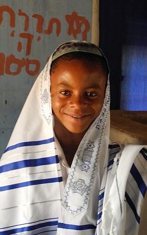 Yehuda wearing a new tallit sent from Israel. Behind him are words from the psalms, 'The Torah of God is Perfect.' (photo credit: Shai Afsai/Times of Israel) Yehuda wearing a new tallit sent from Israel. Behind him are words from the psalms, 'The Torah of God is Perfect.' (photo credit: Shai Afsai/Times of Israel)