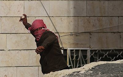 A Palestinian throws stones during a protest in the West Bank village of Se'eer, near Hebron, on February 25, 2013. (photo credit: Issam Rimawi/Flash90