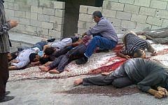 A Syrian man (center), identifies dead bodies who were killed, according to activists, by Syrian forces loyal to Bashar Assad, in Bayda, outside the coastal city of Banias, Syria, on May 2, 2013. (photo credit: AP/The Syrian Revolution Against Bashar Assad)