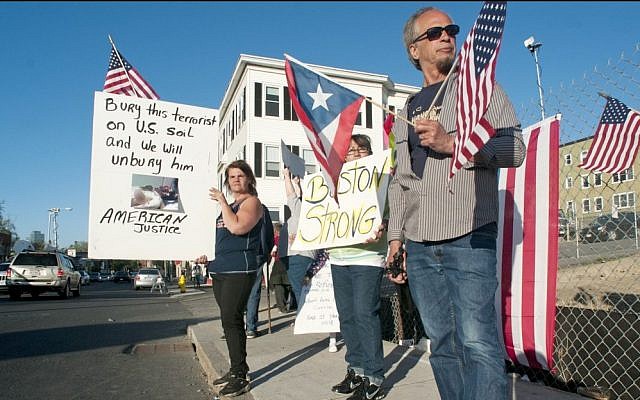 From left, Lisa Taurasi, Lucy Rodriguez and Luis Barbosa, all of Worcester, Mass., hold protest signs as they stand across the street from Graham Putnam & Mahoney Funeral Parlors in Worcester, Mass. on Sunday evening, May 5, 2013. They are upset about the possibility that Boston marathon bombing suspect Tamerlan Tsarnaev may be buried in the United States, and that the body is being held at Graham Putnam & Mahoney Funeral Parlors while a search for a cemetery willing to bury him continues. (photo credit: AP/Worcester Telegram & Gazette, Betty Jenewin) From left, Lisa Taurasi, Lucy Rodriguez and Luis Barbosa, all of Worcester, Mass., hold protest signs as they stand across the street from Graham Putnam & Mahoney Funeral Parlors in Worcester, Mass. on Sunday evening, May 5, 2013. They are upset about the possibility that Boston marathon bombing suspect Tamerlan Tsarnaev may be buried in the United States, and that the body is being held at Graham Putnam & Mahoney Funeral Parlors while a search for a cemetery willing to bury him continues. (photo credit: AP/Worcester Telegram & Gazette, Betty Jenewin)