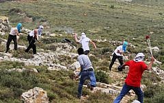 Illustrative photo: Masked Jewish settlers, background, and Palestinians, foreground, hurl stones during clashes in the West Bank, Friday, May 3, 2013. (Issam Rimawi/Flash90)