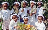 Girls dressed in traditional white dresses hold a basket of fruits and vegetables as they stand in a field, ahead of the upcoming Jewish holiday of Shavuot. (Dudu Greenspan/Flash90)