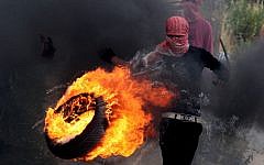 A Palestinian sets fire to a tire during clashes between Palestinians and Israeli soldiers outside the Ofer prison after a march marking the 65th anniversary of the Nakba, or 'Day of Catastrophe,' on Wednesday. (photo credit: Issam Rimawi/Flash90)