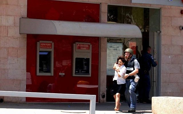 Miriam Cohen, who was held hostage by gunman Itamar Alon in the Bank Hapoalim branch in Beersheba on Monday, is escorted out of the bank after Alon, who killed four people, took his own life (photo credit: Dudu Greenspan/Flash90) Miriam Cohen, who was held hostage by gunman Itamar Alon in the Bank Hapoalim branch in Beersheba on Monday, is escorted out of the bank after Alon, who killed four people, took his own life (photo credit: Dudu Greenspan/Flash90)